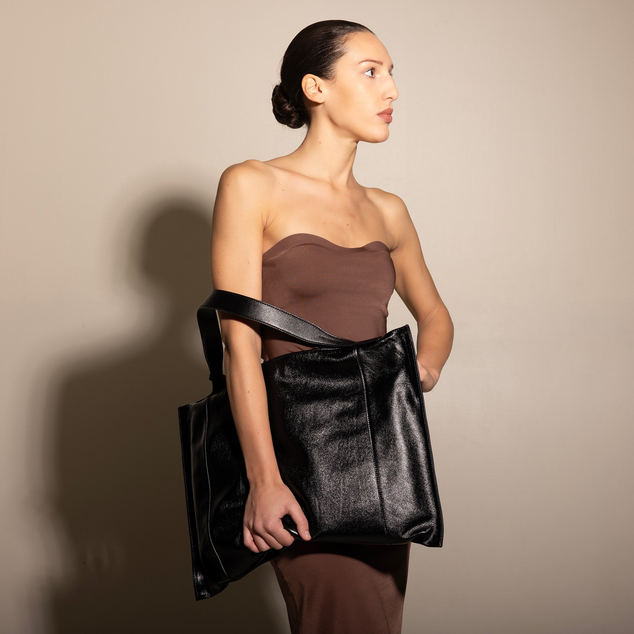 Vittoria Sella Fedra Maxi Bag – smooth black Italian calfskin – model carrying bag at side, three-quarter view, Italian leather bag Made in Veneto